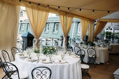 Tabaklar, bıçak, çatal ve buket beyaz çiçek ve yeşillik Merkezi ile tablolarla dekore edilmiş