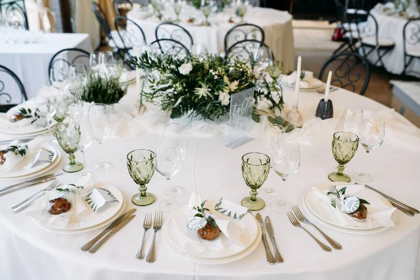 Mesas decoradas com pratos, facas, garfos e buquê com flores brancas e verdes no centro — Fotografia de Stock