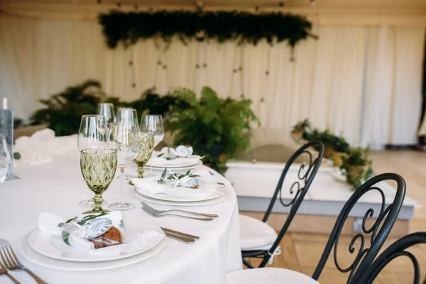 Декоровані столи з тарілками, ножами, виделками і букетом з білими квітами і зеленню по центру — стокове фото