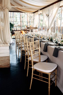 Tablo altın tabaklar, mumlar ve yeşillik üzerinde beyaz masa örtüsü ile dekore edilmiş