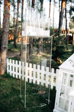 Beyaz ahşap mum lambalar ve çiçeklerle çim açık alan dekore edilmiş