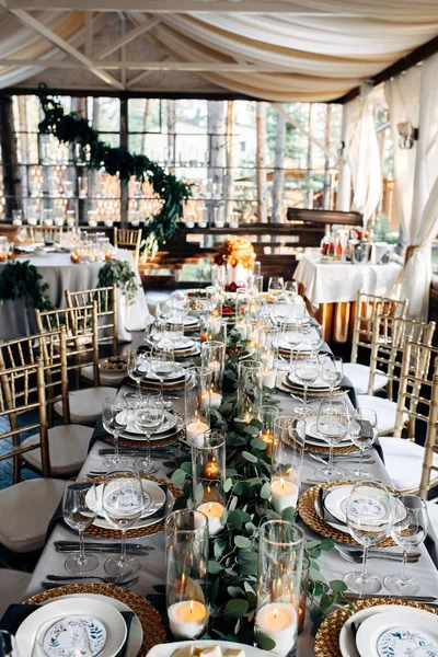 Decorated table with gold plates, candles and greens on the white tablecloth