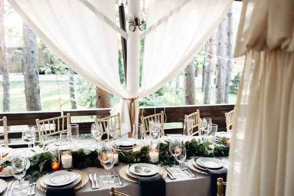 Table décorée avec plaques d'or, bougies et verts sur la nappe blanche — Photo