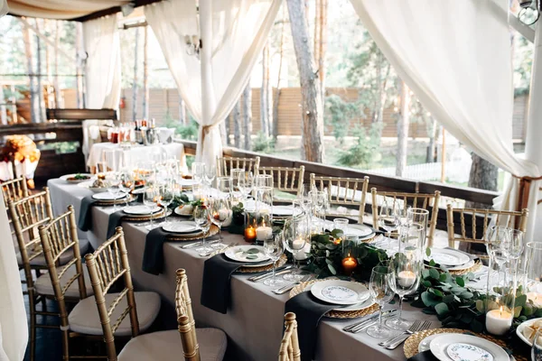 Mesa decorada com placas de ouro, velas e verdes na toalha de mesa branca — Fotografia de Stock