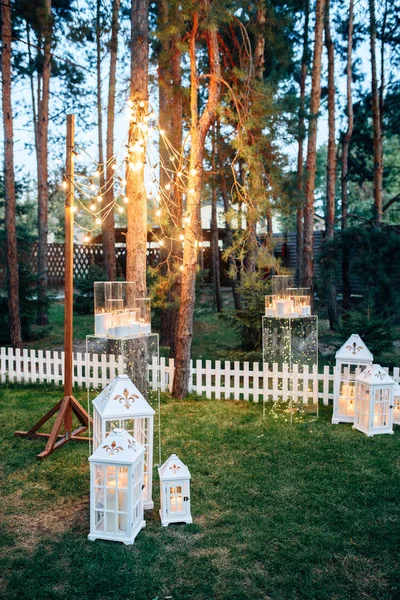 Versierd met witte houten kaars lampen en bloemen op het gras — Stockfoto