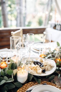 Tablo altın tabaklar, mumlar ve yeşillik üzerinde beyaz masa örtüsü ile dekore edilmiş