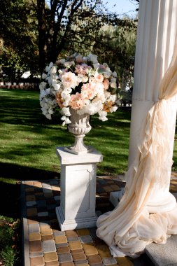 Beyaz düğün kemer beyaz ayakları üzerinde büyük şeftali buketleri ile