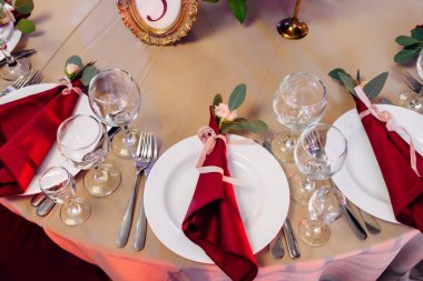 Altın ve bordo renk plakalı, bıçak ve çatal, mumlar ve gözlük, buket çiçek ve yeşillik Merkezi'nde tablolarına dekore edilmiş