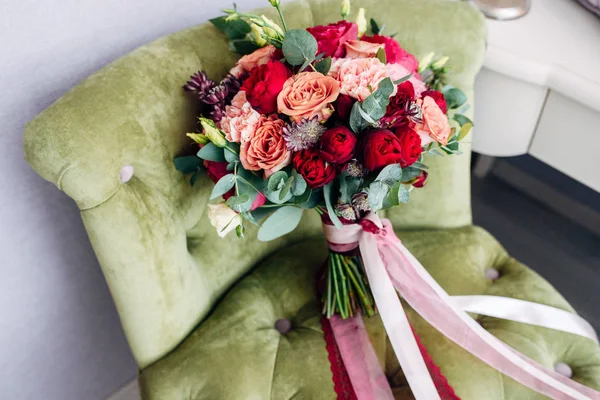 Bukiet ślubny z brzoskwinia i czerwone róże i długie wstążki na fotel z zielony — Zdjęcie stockowe