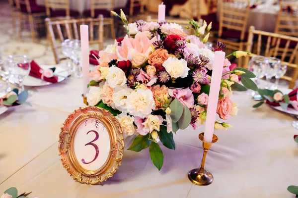 Mesas decoradas em ouro e cores borgonhas com placas, facas e garfos, velas e óculos, buquê com flores e verduras no centavo — Fotografia de Stock