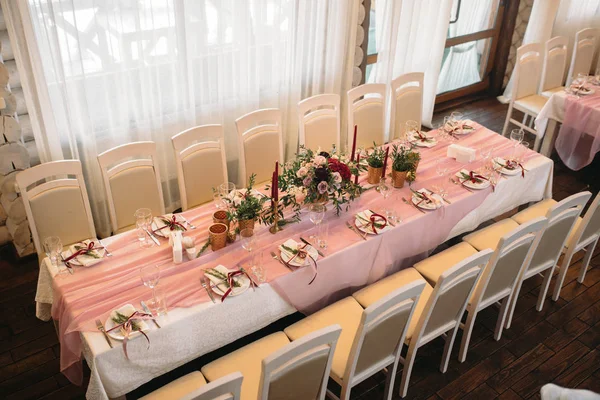 Mesas para hóspedes com cadeiras de cores claras decoradas em cor rosa com flores, velas, vasos de ouro e eucalipto — Fotografia de Stock