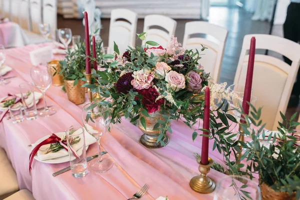 Mesas para hóspedes com cadeiras de cores claras decoradas em cor rosa com flores, velas, vasos de ouro e eucalipto — Fotografia de Stock