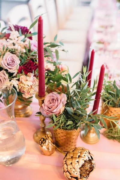 Весільний декор з букетом бордових і рожевих квітів і евкаліпта, бордових свічок в золотих свічках — стокове фото