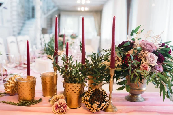 Весільний декор з букетом бордових і рожевих квітів і евкаліпта, бордових свічок в золотих свічках — стокове фото