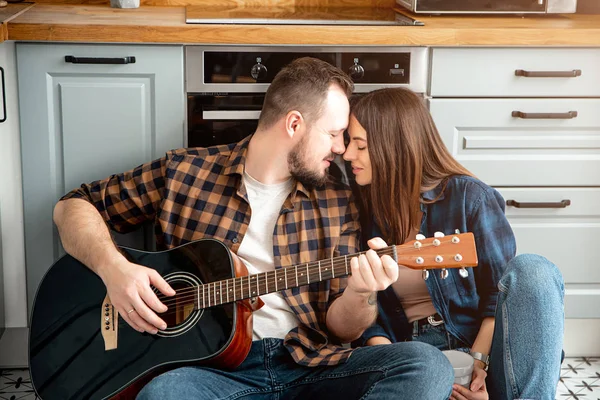 Молода закохана пара на кухні з гітарою — стокове фото