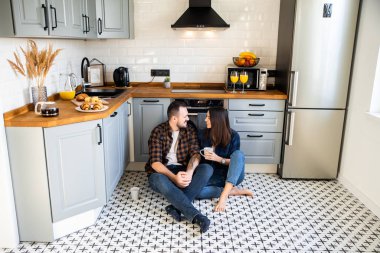 Mutlu çift elinde fincanla yerde oturuyor.