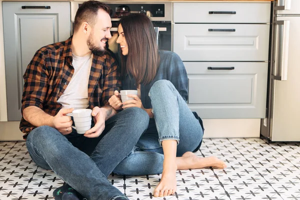 Happy couple sit on the floor with a cups — 스톡 사진