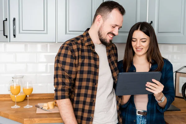 Ragazza con un tablet e un ragazzo in cucina — Foto Stock