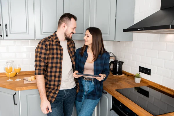 Ragazza con un tablet e un ragazzo in cucina — Foto Stock