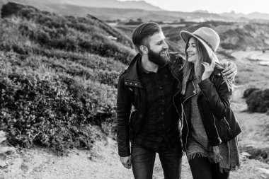 Genç çift bir kayanın üzerinde duruyor ve sarılıyorlar.