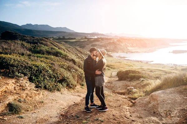 Joven pareja de pie en una roca y besos —  Fotos de Stock