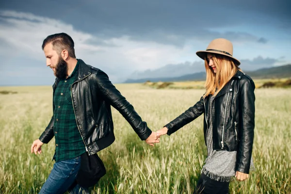 Couple walking on a green field holding hands — 스톡 사진