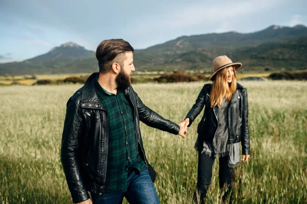 Couple walking on a green field holding hands — 스톡 사진