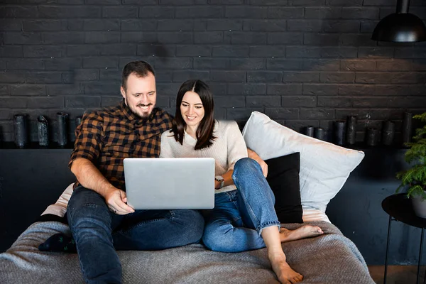 Cuplu cu laptop în haine casual pe pat . — Fotografie, imagine de stoc