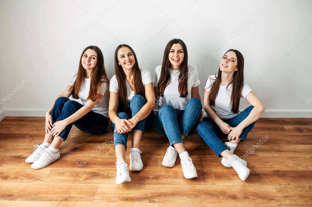 Brunette girls in jeans and t-shirts are sitting
