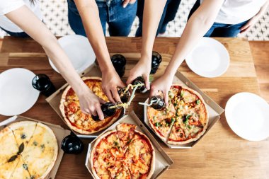 İştah açıcı pizzalar masada ve elleri yukarıda.