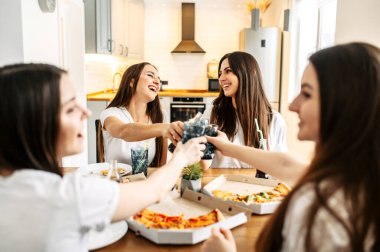 Beyaz tişörtlü genç kızlar pizzayla öğle yemeği yer.