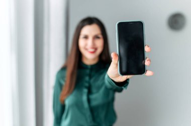 Genç çekici kız akıllı telefonunu gösteriyor.