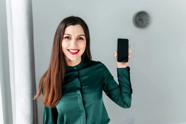 Mladá žena ukazuje svůj smartphone — Stock fotografie
