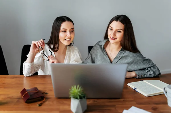 Dos jóvenes empleadas elegantes con un ordenador portátil —  Fotos de Stock