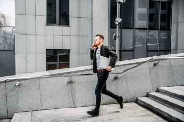 man with a laptop runs up the stairs to the office