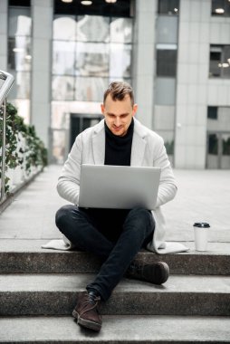 Freelancer with a laptop on the steps outdoors
