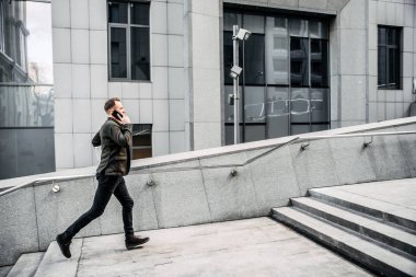 man with a laptop runs up the stairs to the office