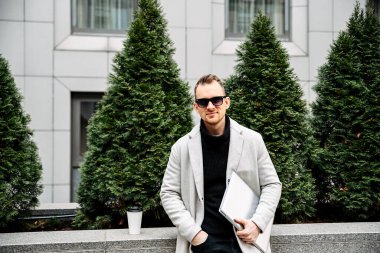 A guy in a smart casual with a laptop outdoor