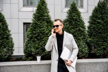 A guy in a smart casual with a laptop outdoor