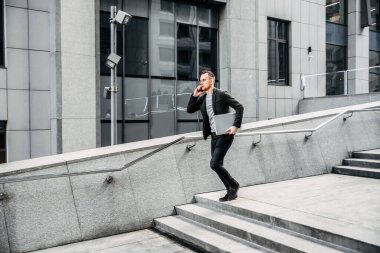 man with a laptop runs up the stairs to the office
