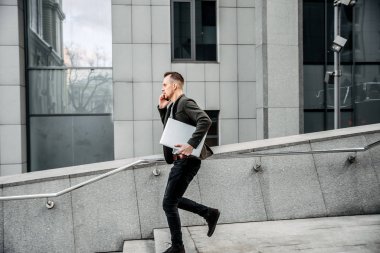 A man with a laptop hurries to a meeting