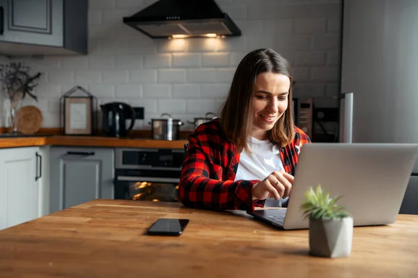Жінка сидить на кухні за допомогою ноутбука — стокове фото