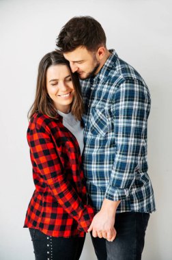 Birbirine aşık bir çift beyaz bir arka planda sarılıyor.