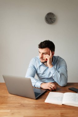 Gömlekli bir ofis çalışanı dikkatlice düşünür.