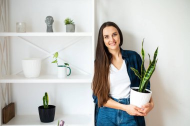 Young woman holds a flower pot in her hands