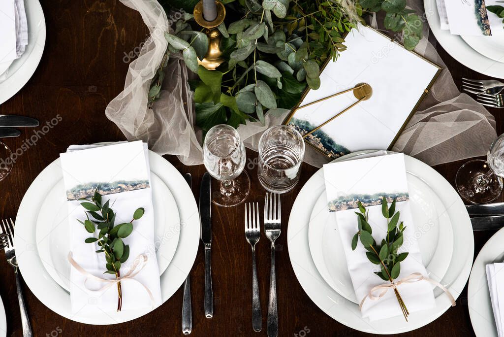 White napkin with eucalyptus and guest card on it