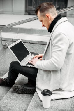 Freelancer with a laptop on the steps outdoors