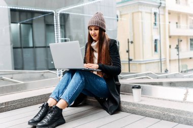 Diz üstü bilgisayarı olan serbest çalışan kız dışarıda çalışıyor.