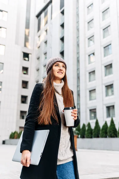 Uma menina atraente na paisagem urbana com laptop — Fotografia de Stock