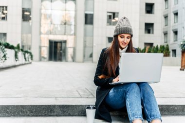 Dizüstü bilgisayarı olan bir kadın merdivenlerde oturuyor.